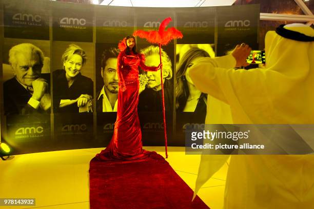 Saudi moviegoer takes a picture of a woman in costume during the opening of the AMC Entertainment cinema theatre at the King Abdullah Financial...