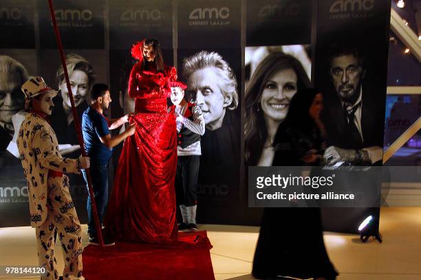 Dpatop - Two men fixes the dress of a woman in costume during the opening of the AMC Entertainment cinema theatre at the King Abdullah Financial...