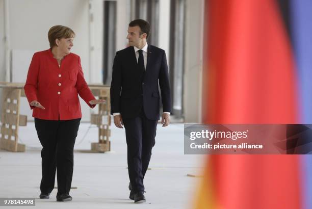 April 2018, Germany, Berlin: German Chancellor Angela Merkel and French President Emmanuel Macron on their way to a press conference after their...