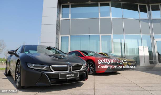 April 2018, Germany, Leipzig: Three BMW i8 vehicles in black, red and gold outside the BMW plant in Leipzig. The plug-in hybrid sports car has been...