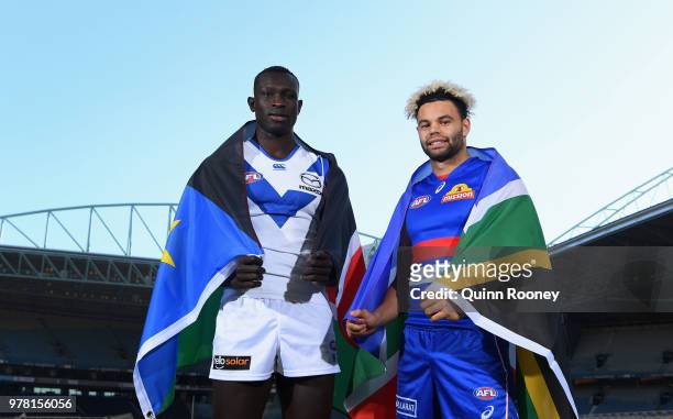 Majak Daw of the Kangaroos and Jason Johannisen of the Bulldogs pose with their national flags during an AFL press conference at Etihad Stadium on...