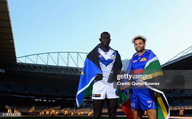 Majak Daw of the Kangaroos and Jason Johannisen of the Bulldogs pose with their national flags during an AFL press conference at Etihad Stadium on...