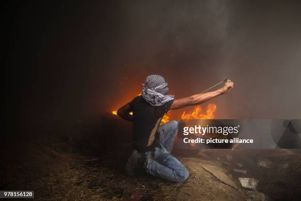 Palestinian protester uses a sling to hurl stones at Israeli security forces during clashes along the Israel-Gaza border, east of Gaza City, Gaza...