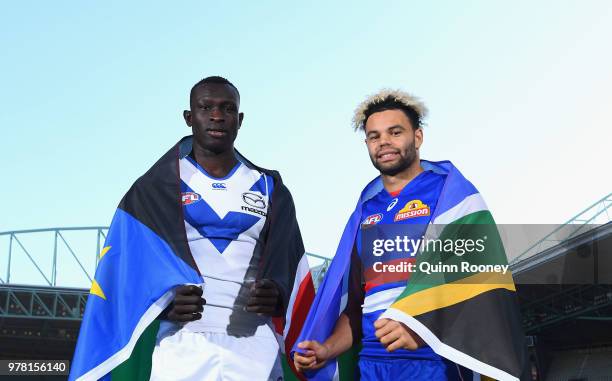 Majak Daw of the Kangaroos and Jason Johannisen of the Bulldogs pose with their national flags during an AFL press conference at Etihad Stadium on...