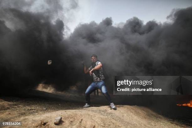 Dpatop - A Palestinian protester uses a sling to hurl stones at Israeli security forces during clashes along the Israel-Gaza border, east of Gaza...