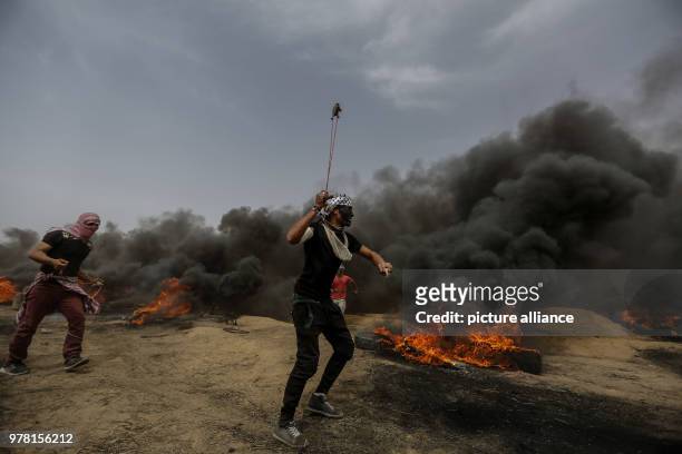 Dpatop - A Palestinian protester uses a sling to hurl stones at Israeli security forces during clashes along the Israel-Gaza border, east of Gaza...