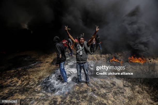 Palestinian protester flashes a victory sign during clashes with Israeli security forces along the Israel-Gaza border, in Khan Younis, south of the...