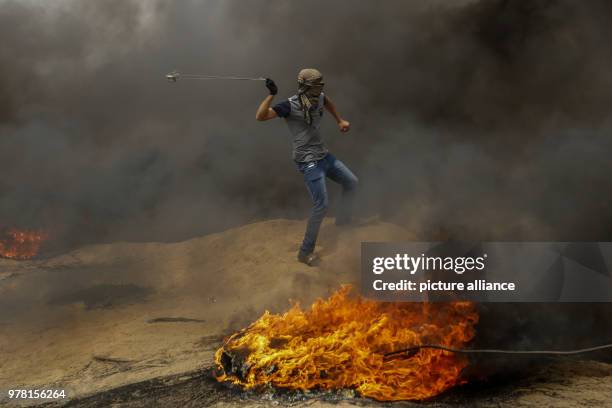 Dpatop - A Palestinian protester uses a sling to hurl stones at Israeli security forces during clashes along the Israel-Gaza border, east of Gaza...