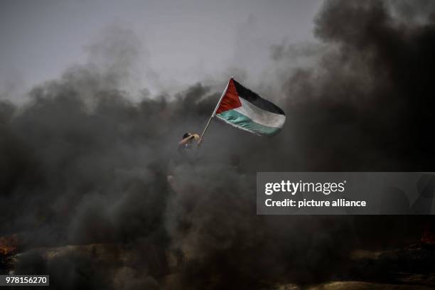 Dpatop - A Palestinian protester holds his national flag during clashes with Israeli security forces along the Israel-Gaza border, east of Gaza City,...