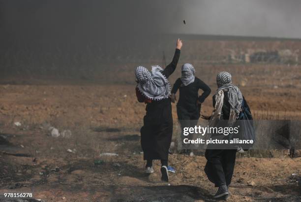 Dpatop - Palestinian protesters hurl stones at Israeli security forces during clashes along the Israel-Gaza border, east of Gaza City, Gaza Strip, 20...