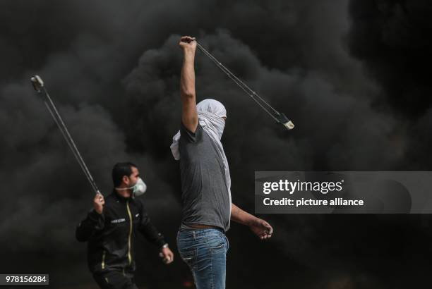 Dpatop - A Palestinian protester uses a sling to hurl stones at Israeli security forces during clashes along the Israel-Gaza border, east of Gaza...