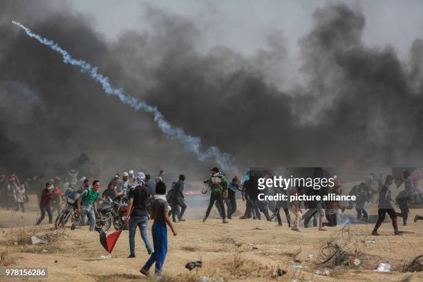 Palestinian protesters burn tyres while Israeli security forces fire tear gas canisters during clashes along the Israel-Gaza border, east of Gaza...