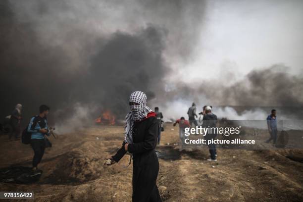 Palestinian woman holds a stone to hurl at Israeli security forces during clashes along the Israel-Gaza border, east of Gaza City, Gaza Strip, 20...