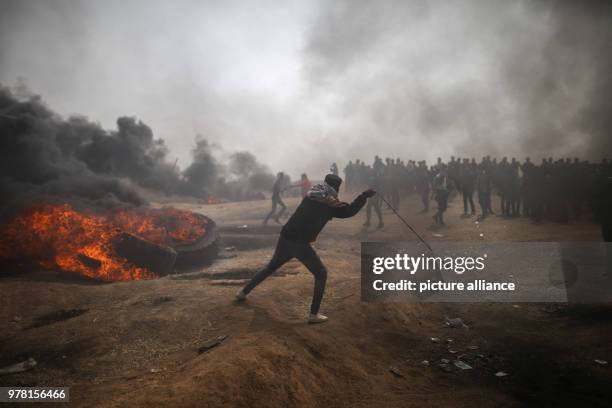 Palestinian protester uses a sling to hurl stones at Israeli security forces during clashes along the Israel-Gaza border, east of Gaza City, Gaza...