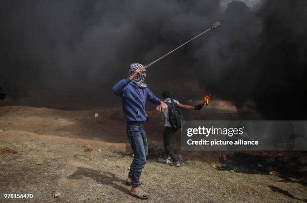 Palestinian protester uses a sling to hurl stones at Israeli security forces during clashes along the Israel-Gaza border, east of Gaza City, Gaza...