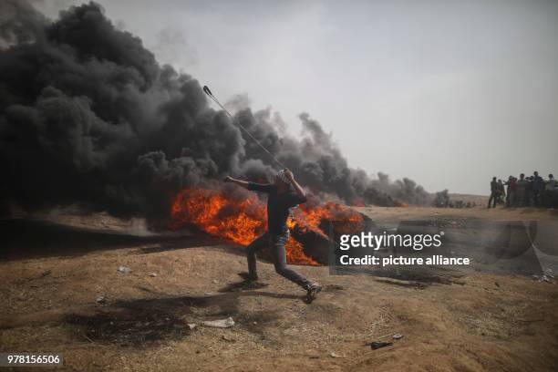 Dpatop - A Palestinian protester uses a sling to hurl stones at Israeli security forces during clashes along the Israel-Gaza border, east of Gaza...