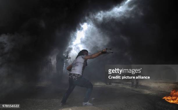 Palestinian protester uses a sling to hurl stones at Israeli security forces during clashes along the Israel-Gaza border, east of Gaza City, Gaza...