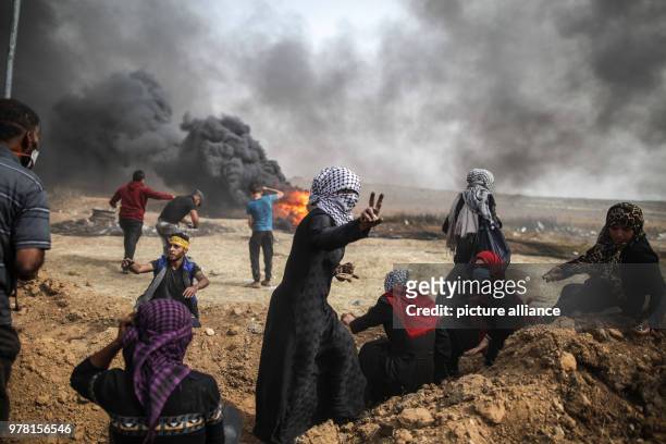Dpatop - A Palestinian woman flashes a victory sign during clashes with Israeli security forces along the Israel-Gaza border, east of Gaza City, Gaza...