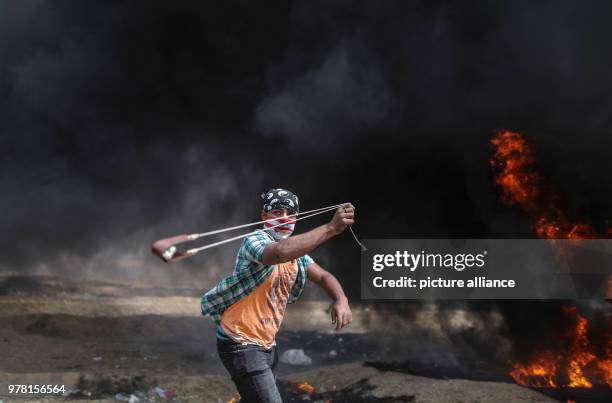 Dpatop - A Palestinian protester uses a sling to hurl stones at Israeli security forces during clashes along the Israel-Gaza border, east of Gaza...