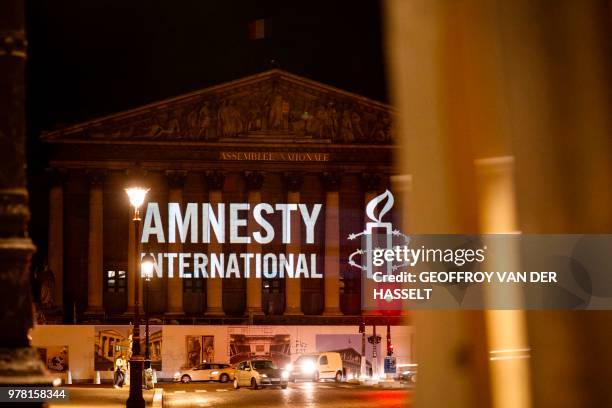 The logo of NGO Amnesty International is projected onto the Palais Bourbon, the seat of the French national assembly, late on June 18, 2018. - The...