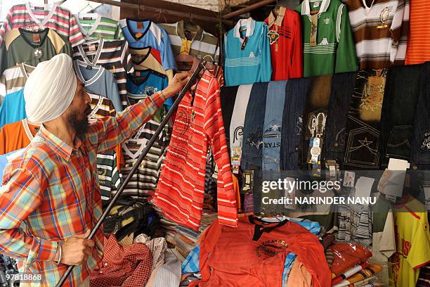 Indian vendor Niranjan Singh displays T-Shirts on display at his garment stall in Amritsar on March 18 , 2010. AFP PHOTO/NARINDER NANU