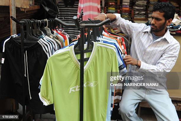 Indian vendor Surinder Kumar Shukla displays T-Shirts on display at his garment stall in Amritsar on March 18 , 2010. AFP PHOTO/NARINDER NANU