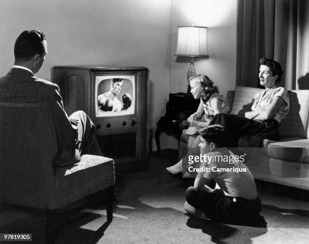 Family watching a boxing match on television in their home, circa 1950.