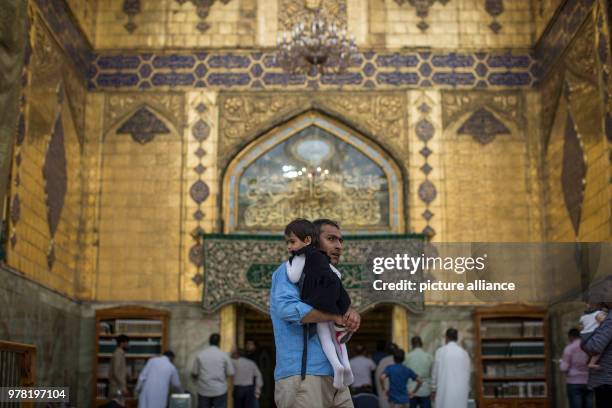 Shiite Muslim man carries his daughter in the Imam Ali Mosque in Najaf, Iraq, 21 April 2018. The site is believed to be burial place of Ali, the...