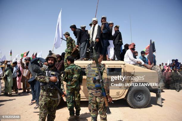 In this photo taken on June 17 Afghan Taliban militants and residents stand on a armoured Humvee vehicle of the Afghan National Army as they...
