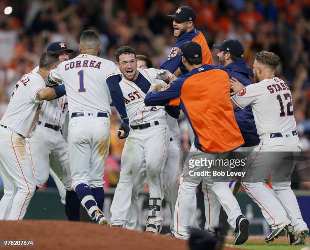 Alex Bregman of the Houston Astros is mobbed by his teammates after hitting a walkoff double in the ninth inning against the Tampa Bay Rays for a 5-4...