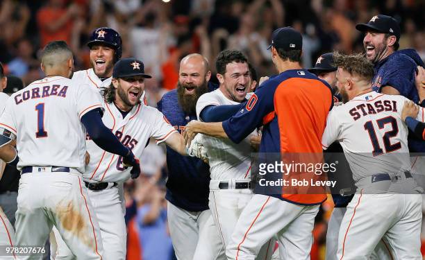 Alex Bregman of the Houston Astros is mobbed by his teammates after hitting a walkoff double in the ninth inning against the Tampa Bay Rays for a 5-4...