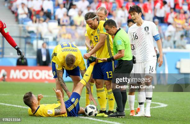 Mikael Lustig of Sweden is helped for his cramps by Gustav Svensson while referee Joel Aguilar of Salvador looks on during the 2018 FIFA World Cup...