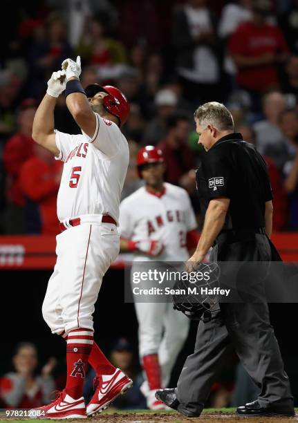 Albert Pujols of the Los Angeles Angels of Anaheim reacts after hitting a solo homerun during the fourth inning of a game as umpire Greg Gibson looks...