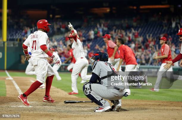 Carlos Santana of the Philadelphia Phillies scores the game winning run as teammates celebrate after Aaron Altherr hit a two-run double in the 10th...
