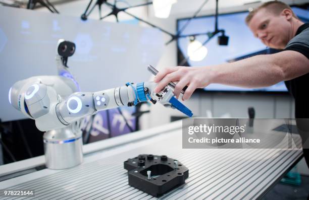 April 2018, Hanover, Germany: Developer Christian Trapp interacts with a robot arm at the Hannover Messe on the Festo stand. With the...