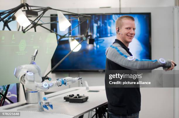 April 2018, Hanover, Germany: Developer Christian Trapp interacts with a robot arm at the Hannover Messe on the Festo stand. With the...