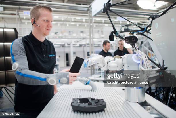 April 2018, Hanover, Germany: Developer Christian Trapp interacts with a robot arm at the Hannover Messe on the Festo stand. With the...