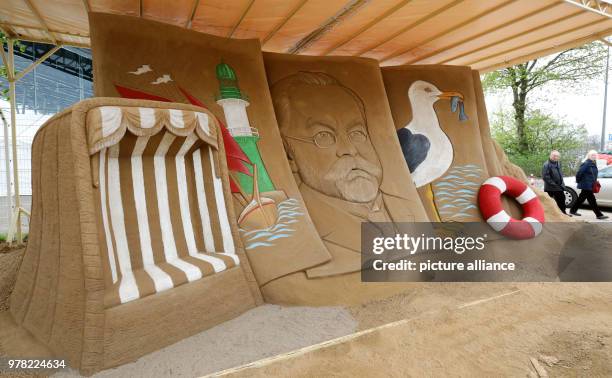 April 2018, Germany, Warnemuende: Visitors walk past the sculpture by Pavel, Daria and Jaroslava Mylnikov from Russia on the topic of the Baltic Sea...