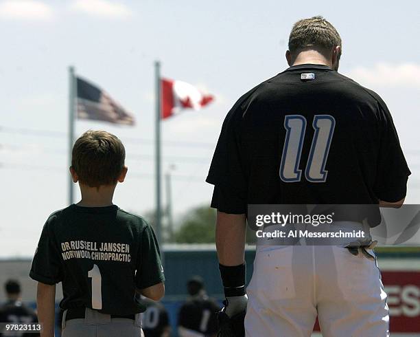 Toronto Blue Jays infielder Eric Hinske lines up at third base with a Little League ball player before play against the Cleveland Indians in Dunedin,...