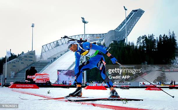 Martin Fourcade of France crosses the finish line close to the new Holmenkollen ski jump hill as he competes to take the first place of the 10km...