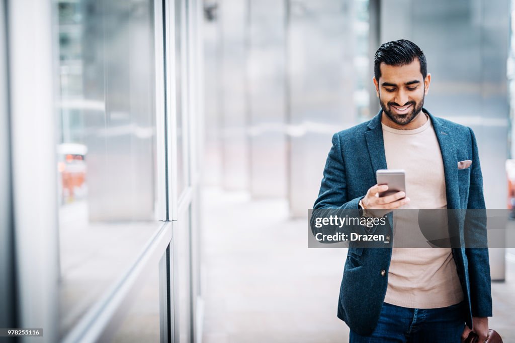 Businessman using smart phone near office building