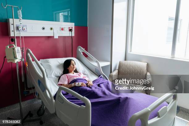 malaysian girl in hospital bed looking out of window - sad child hospital stock pictures, royalty-free photos & images