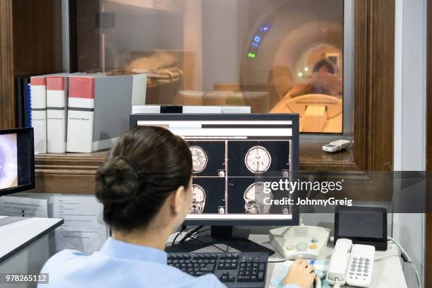 radiographer looking at mri scan on computer screen - tomografia por emissão de positrões imagens e fotografias de stock