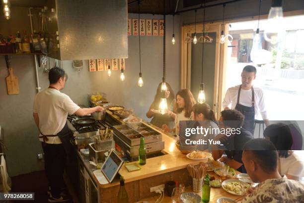varios amigos étnicos disfrutando de una cena en el bar japon - edificio de hostelería fotografías e imágenes de stock