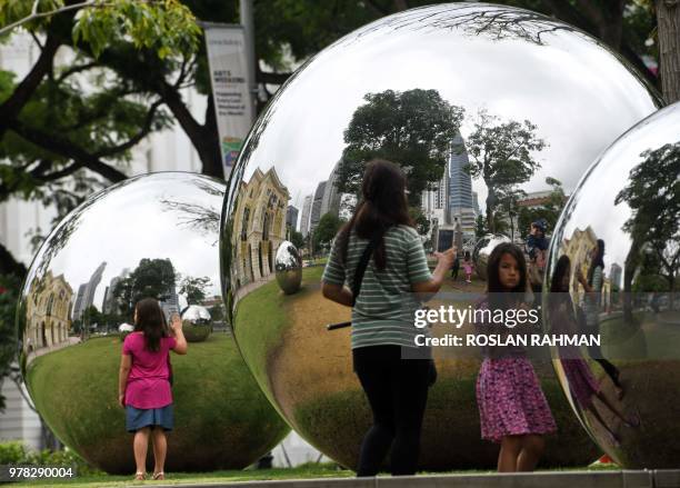 People stands around a reflective arts installation outside Asian Civilisation Museum in Singapore on June 19, 2018.