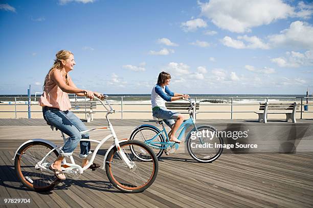 two women cycling on boardwalk - paso entablado fotografías e imágenes de stock