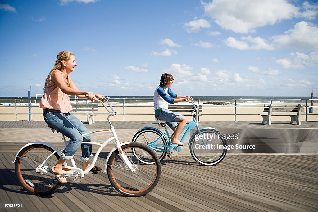 Two women cycling on boardwalk