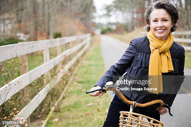 mature woman on a bicycle - vrouw 50 jaar stockfoto's en -beelden