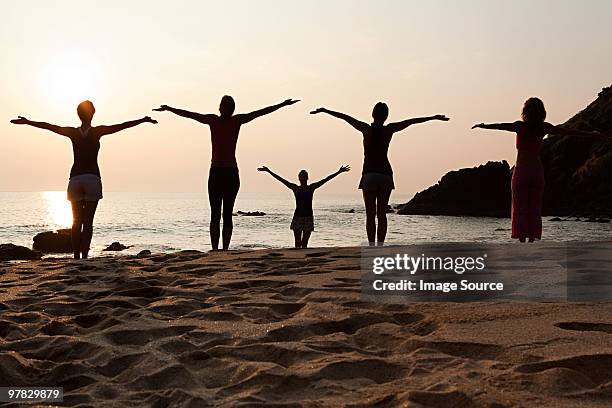 women practicing yoga on beach at sunset - yoga goa woman stock pictures, royalty-free photos & images