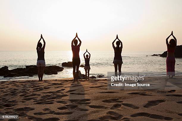 women practicing yoga on beach at sunset - goa beach bildbanksfoton och bilder
